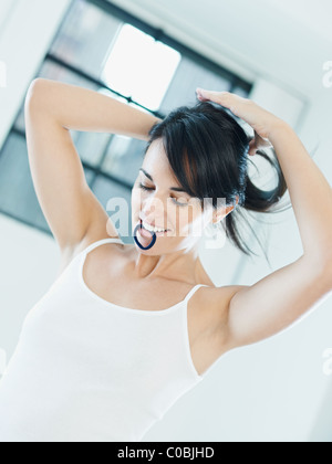woman tieing hair with rubber band in mouth Stock Photo