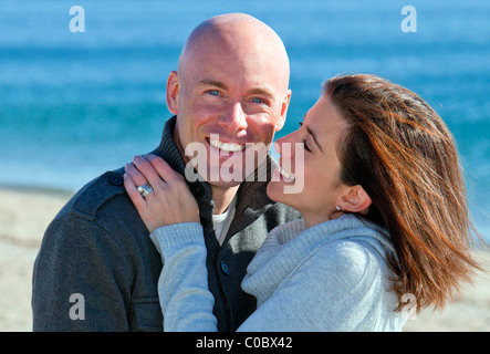 Handsome young couple hugging at the beach in winter Stock Photo