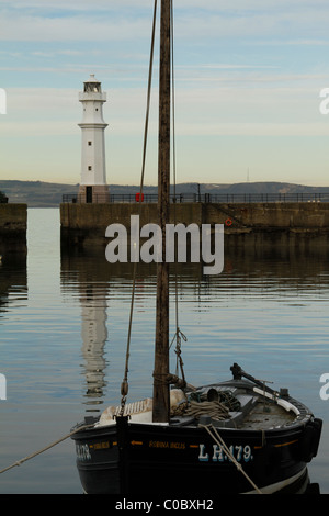 Dusk settles over Newhaven Harbour, Edinburgh. Lighthouse reflected in the calm water, looking northwards towards Fife coast Stock Photo
