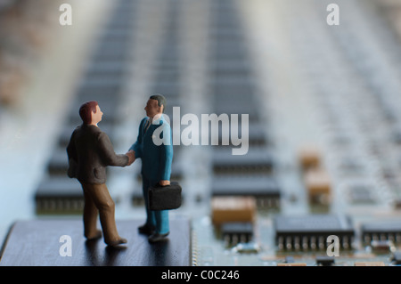 Miniature figures shaking hands on a circuit board Stock Photo