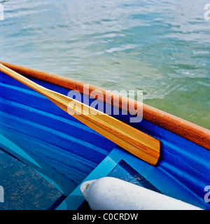A cropped image of a rowing boat with a buoy and an oar resting inside. Stock Photo