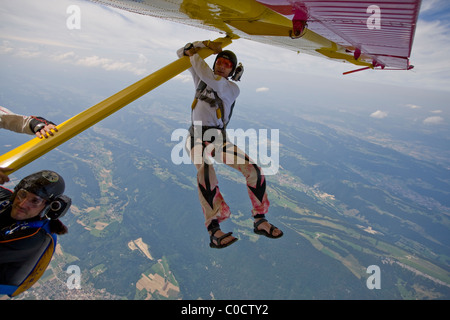 Skydiver is holding on wing of plane before he is jumping off it. Stock Photo