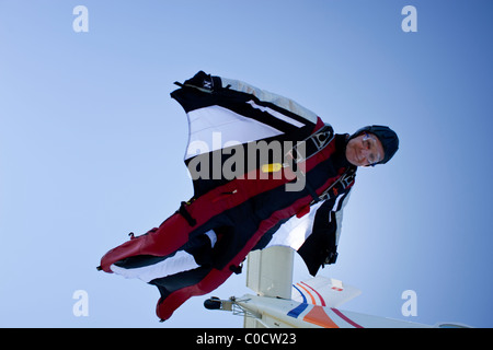 Skydiver within special wingsuit is jumping out of a plane in the blue sky. Stock Photo