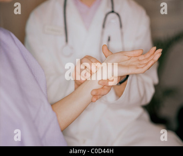 Doctor taking female patient's pulse Stock Photo