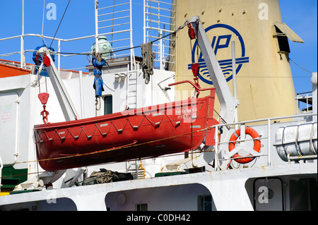 Orange lifeboat on the Thisseas, a Greek tanker ship moored in the port of Katapola, on the Greek Cyclade island of Amorgos. Stock Photo