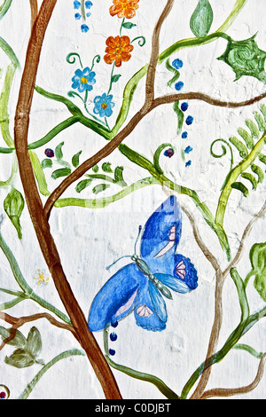 fresh whimsical wall painting with beautiful blue butterfly & flowering vines on side wall of outside door jamb opening to street Oaxaca City Mexico Stock Photo