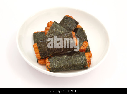 Japanese arare rice crackers wrapped in nori on a white dish. Stock Photo