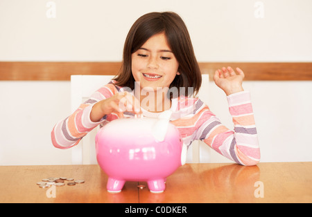 Little girl putting her money in a piggy bank Stock Photo