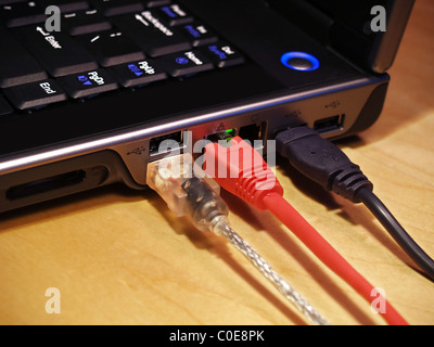 Closeup image of a laptop computer with three cables plugged into the ports Stock Photo