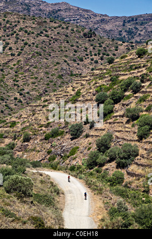 Two cyclists on dirt road through mountains Parc Natural de Cap de Creus Emporda Catalunya Spain Stock Photo