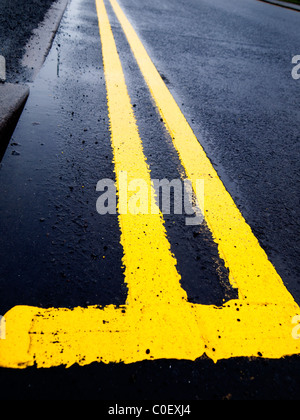 Road marking a newly painted double yellow line on a wet road Stock Photo