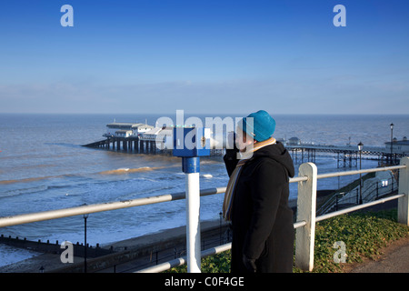 A tourist looks out to sea with 'Cromer Pier' in the background' North Norfolk' UK Stock Photo