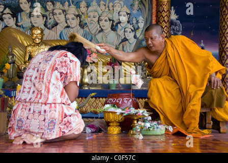 Thailand, Ko Samui (aka Koh Samui). Locals being blessed by Buddhist monk in front of the Temple of Big Buddha on Fan Island. Stock Photo