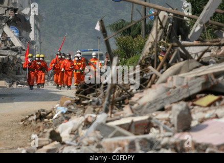 The rescue workers pass the ruins from the earthquake in Beichuan county, Sichuan province. Beichuan County, China - 19.05.08 Stock Photo