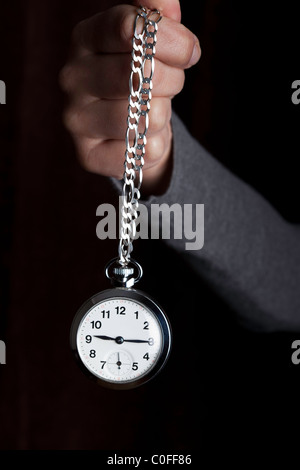 Pocket watch swinging on a chain to hypnotise , black background Stock ...