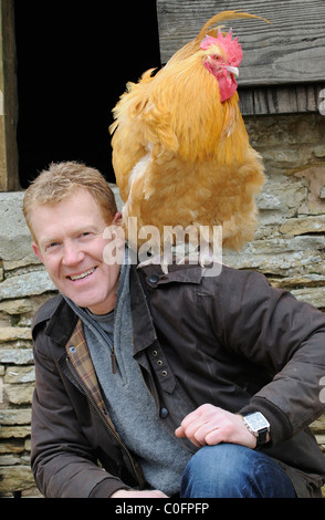 Adam Henson Cotswold farmer at Adam's farm. BBC Countryfile presenter with rare breeds Buff Orpington chicken on his shoulder Stock Photo