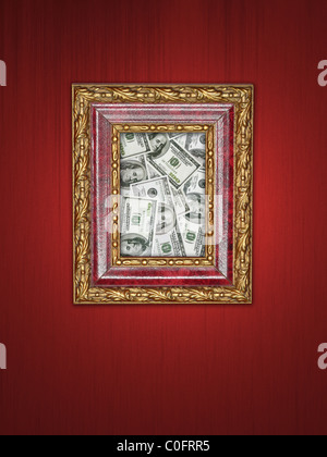 Pile of one hundred dollar banknotes in wooden picture frame with golden ornaments hanging on purple wall Stock Photo