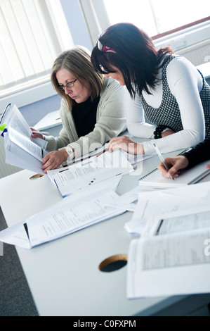 Two women Adult learners on day-release studying learning working reading notes at a college of further education UK Stock Photo