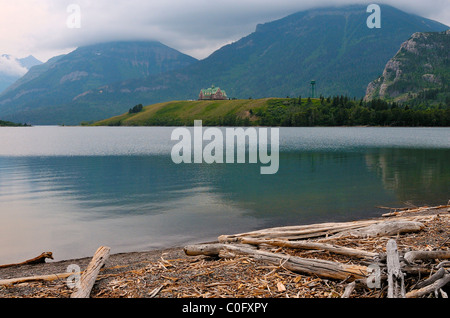 A landscape view of the shore on Waterton lake with mountains and the Prince of Wales hotel in the background. Stock Photo