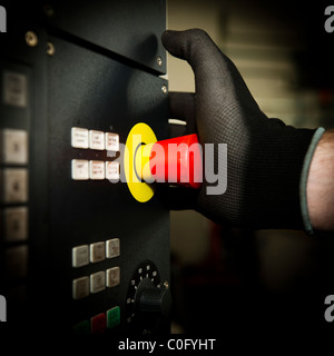 a man pressing the emergency stop button on a machine in a factory or workshop uk Stock Photo