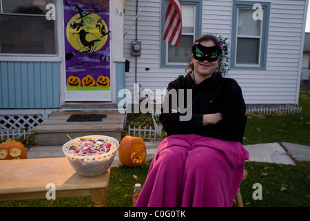 A young costumed  woman waits for trick or treaters to arrive in the late afternoon on Halloween. Stock Photo