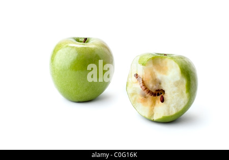 Two green apples, one half eaten with a worm crawling out of the center. Stock Photo