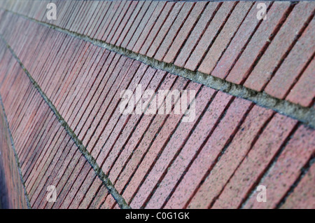 Angled red brick wall trailing in diminished perspective to the left Stock Photo