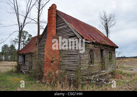 An old, dilapidated building sitting in a field. Stock Photo