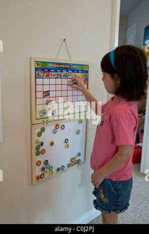 Hispanic 6 year old girl places tiles on her responsibility chart at her home in Austin, Texas, USA Stock Photo