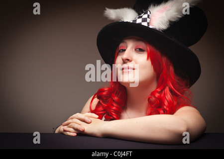Sultry Red Haired Woman Wearing Bunny Ear Hat on a Grey Background. Stock Photo