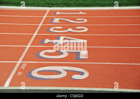 Lanes of a red race track with numbers and green football field Stock Photo