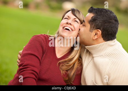 Attractive Mixed Race Couple Snuggle in the Park. Stock Photo