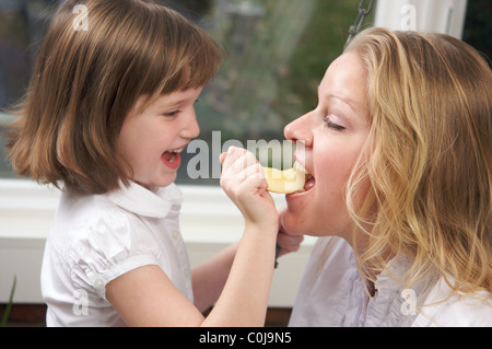 Daughter Having Fun Feeding Mom an Apple Slice Stock Photo