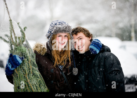 A young couple with a Christmas tree in the snow Stock Photo