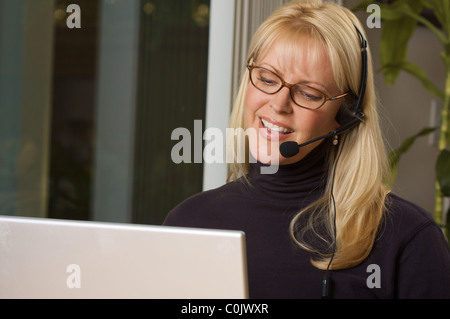 Attractive businesswoman smiles as she talks on her phone headset. Stock Photo