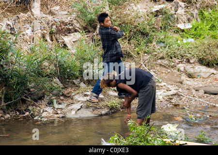 Two Burmese teenage boys are bathing in a dirty and polluted river in Tachilek, Burma (Myanmar). Stock Photo