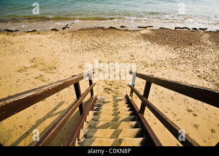 Wooden stairs leading down to a sandy beach at low tide - 2 Stock Photo