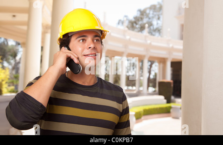 Handsome Hispanic Contractor with Hard Hat Talking on His Cell Phone. Stock Photo