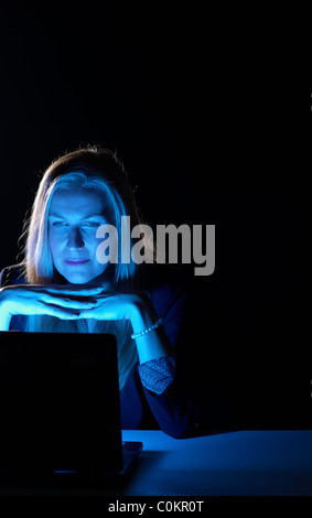 Businesswoman working late hours, concentrated on the laptop screen Stock Photo