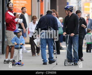 Matthew Broderick takes his son James to school. The pair ride scooters along the sidewalk wearing crash helmets for safety New Stock Photo