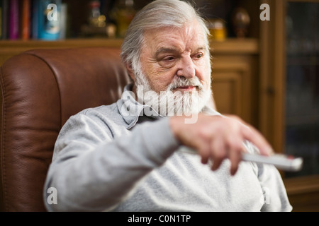Senior man at home holding remote control Stock Photo