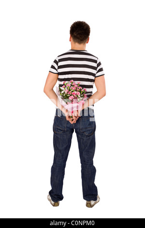 Casual young man standing back to the camera hiding bouquet of flowers behind his back, isolated on white background Stock Photo