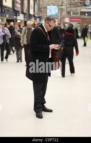 Business man using his mobile PDA device at Waterloo railway station London Stock Photo