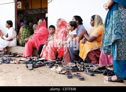 Keralite women and children sit outside a full church in a village outside Cochin, Kerala, India Stock Photo