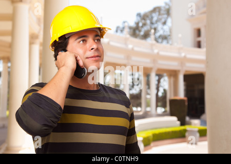 Handsome Hispanic Contractor with Hard Hat Talking on His Cell Phone. Stock Photo