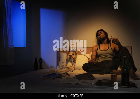 Man smoking on the bed with wine Stock Photo