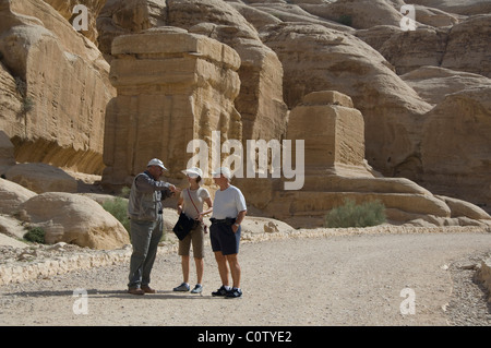 Jordan, Ancient Nabataean city of Petra. Tourists with guide in front of ruins of the Djinn Blocks. Stock Photo