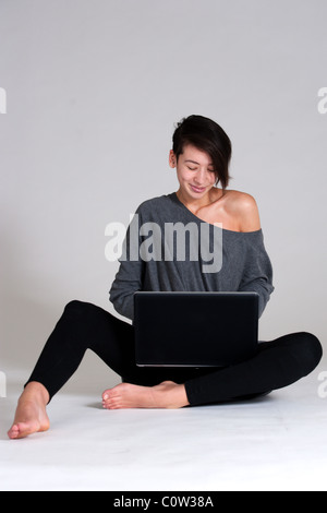 Studio shot of a multi raced yopung woman with her laptop on the floor Stock Photo