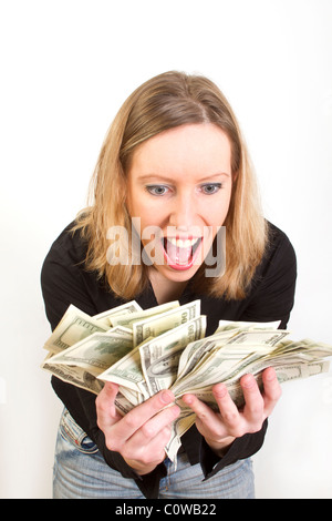 Young woman have lots of dollars in her hands and looking pleasantly surprised Stock Photo