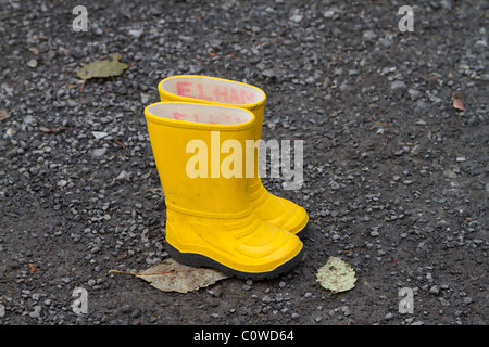 Yellow wellies. A pair of bright yellow child's wellington boots on a gravel path Stock Photo